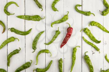 Leadership concept - red hot chili pepper leading the group of green peppers