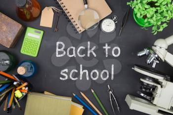 Education concept - books, microscope and Back to school inscription on the blackboard