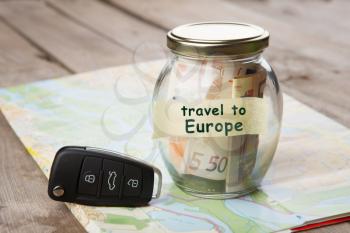 Travel by car to Europe - money jar, car key and roadmap