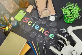Education concept - books, microscope and Science inscription on the blackboard
