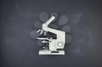 Science concept - microscope on the table in the auditorium, blackboard background