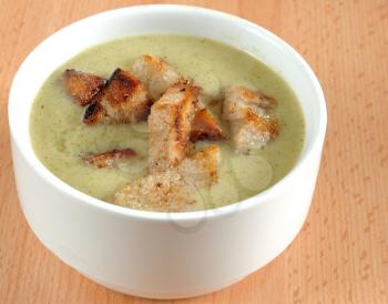 Close-up image of broccoli soup in white dish with crouton.
