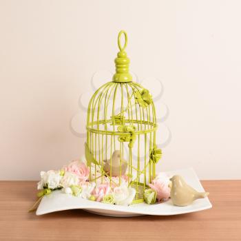 Interior decoration, decorative bird cage with small porcelain birds and rose.