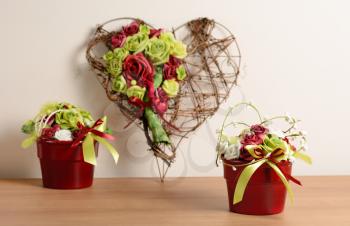 Interior decoration, decorative set with wicker heart and red flowerpot with rose.
