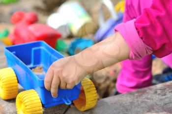 Children hand keep the plastic carriage toy at sandpit.