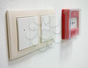 White light switch with fire alarm button on the wall.