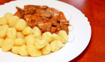 Beef Stroganoff with potato gnocchi in white plate.