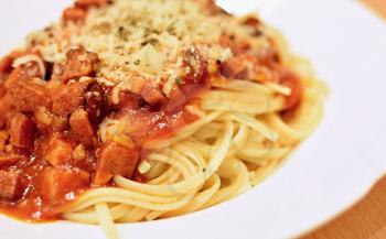 Spaghetti with tomato sauce, sausages sprinkled with grated cheese on the white plate.