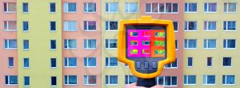 An infrared thermal imager showing building facade and windows heat loss.