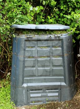 Old dirty composter bin with rotten grass.
