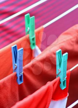 Clothespins on clothesline securing the red wet clothes. Red wet clothes drying on clothesline securing with clothespins.