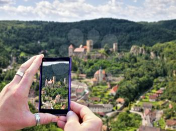 View over the mobile phone display during taking a picture of Hardegg village. Holding the mobile phone in hands and taking a photo. Focused on mobile phone screen.	