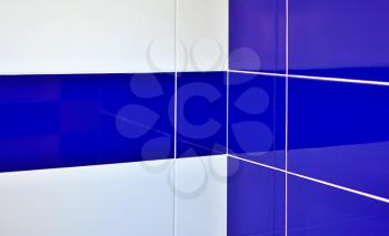 Blue and white gloss tiles with white joints in bathroom corner.