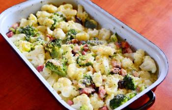 Baked Cauliflower and Broccoli with Grated Parmesan and Pieces of Bacon in Black Pan.