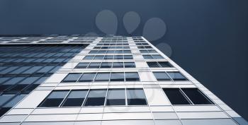 Low angle abstract perspective view of modern commercial office building with lot of windows against the sky.