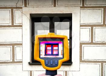 An infrared thermal imager showing building facade and window heat loss.