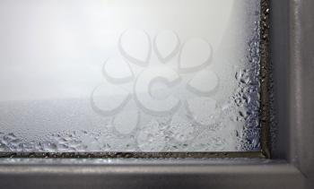 Closeup of the winter condensation on the inside of a window, insulation failure. A window glass covered with condensation drops.