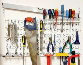 Front view of the white tool board with various hanged tools.
