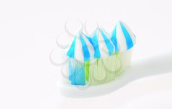 Macro shot of toothbrush head with toothpaste on white background.