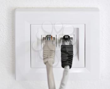 Two data patch cords plugged into a wall data internet RJ45 socket.