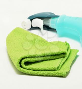 A green rag and bottle of a detergent on white background. A disinfection or cleaning concept.