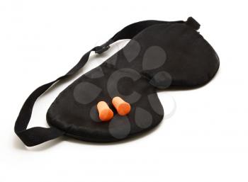 Black sleep eye mask with pair of orange foam ear plugs over white background.