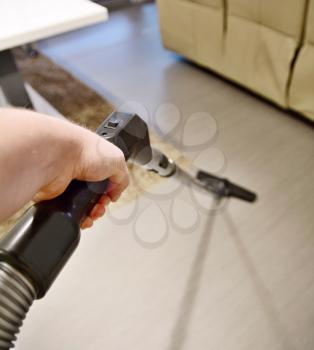 Man hand holding vacuum cleaner tube and makes housework and vacuuming the floor in room. Closeup point of view or first person view shot.