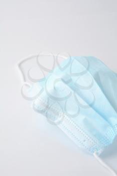 Blue surgical face mask (currently protecting against Coronavirus Covid-19) on white background.