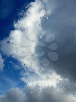 Raindrops on the window during stormy and rainy weather. View of dark clouds behind the window.