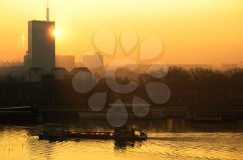Sun going behind the building and view of the river Sava with thanker ship and urban scape of Belgrade city