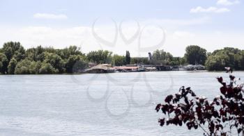 Boats  and rafts anchored on Danube river with beautiful blue sky and trees in background