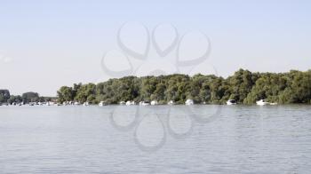 Boats anchored on Danube river with beautiful blue sky and trees in background