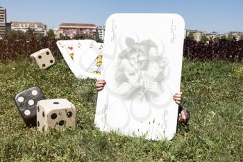 Large Joker Card, Dices and Girl Behind It Outdoors