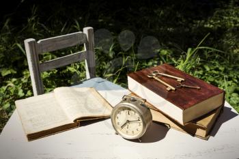 Vintage still life with old alarm clock, keys and books on a white wooden table