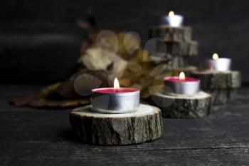 Christmas candles burning, decoration on wooden logs resting on rustic wooden background