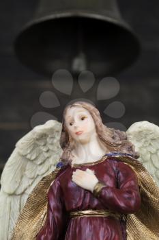 Angel Figurine with White Wings Standing Beneath Church Bell