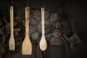 Kitchen Utensils Hanging On A Rope Against Rustic Wooden Background