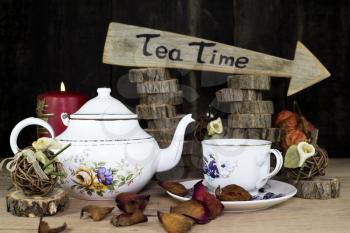 Cup of Tea and Teapot On Wooden Table. Arrow Sign With Text, Tea Time Written On It in The Background