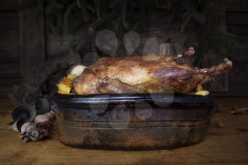 Christmas Duck Roast At The Wooden Table With Wood Logs and Pine Branches In The Background