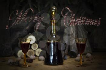 Merry Christmas Sign With Red Wine Vintage Bottle and Glasses Resting On Wooden Table With Stardust and Snowflakes in The Background