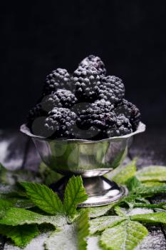 Blackberries Served With Sprinkled Powdered Sugar and Blackberry Leaves On Rustic Wooden Table