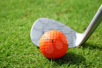 Golf club and orange golf ball