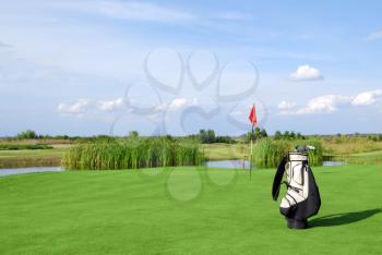 Golf field with flag and golf bag