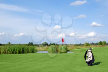 Golf field with red flag and white golf bag