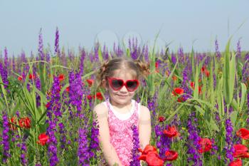 little girl standing in meadow with colorful flowers