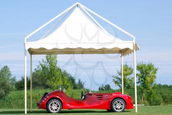 Fast red cabriolet car under white tent