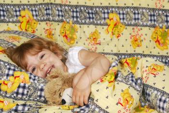 Little girl lying in bed with teddy-bear