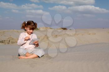 happy little girl play with tablet pc in desert