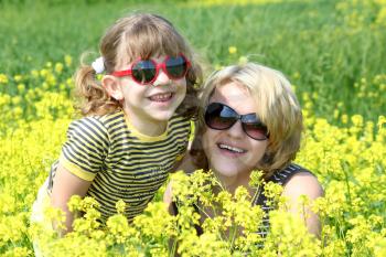 happy mother and daughter in yellow flowers field