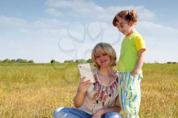 mother and daughter with tablet in field
